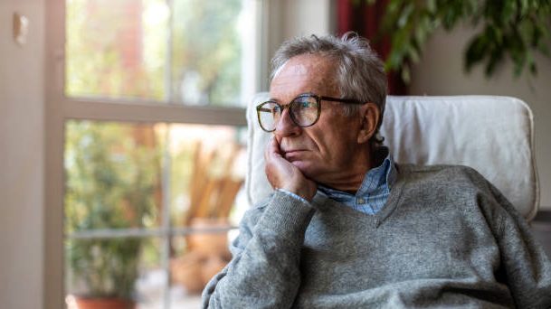Senior man looking out of window at home